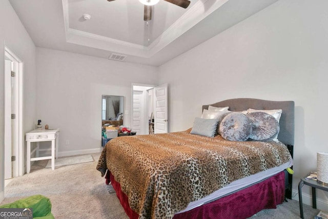 carpeted bedroom featuring ceiling fan, visible vents, baseboards, ornamental molding, and a tray ceiling