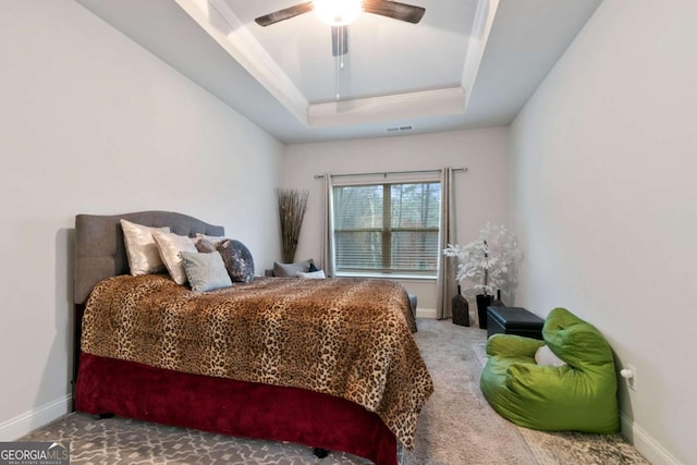 carpeted bedroom with baseboards, visible vents, ceiling fan, and a raised ceiling