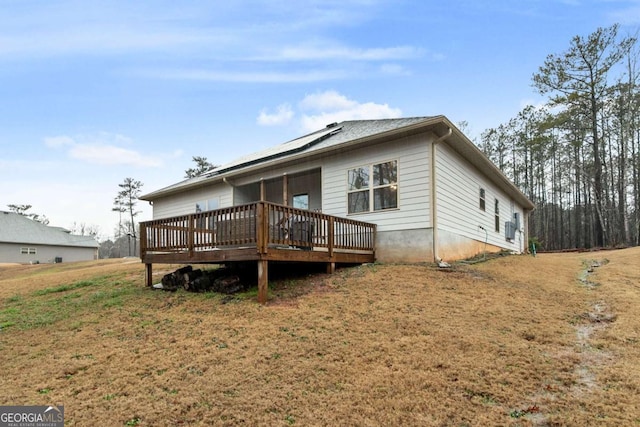 rear view of house featuring a yard, solar panels, and a deck