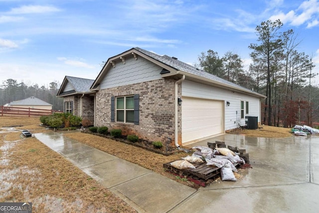 view of side of property with fence, an attached garage, brick siding, central air condition unit, and driveway