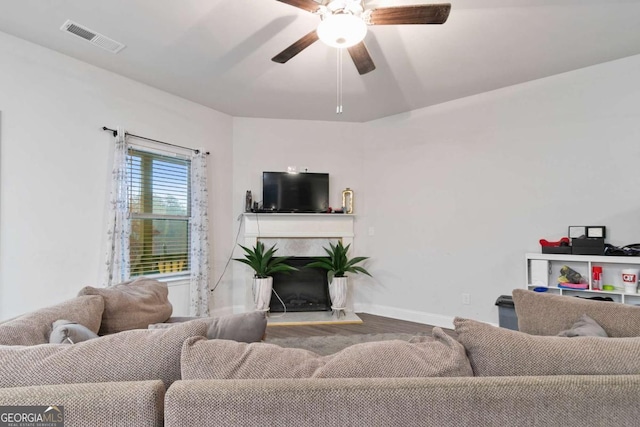 living room with a ceiling fan, visible vents, a high end fireplace, wood finished floors, and baseboards