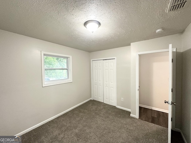 2930 Waters Rd, Atlanta, GA 30354 - unfurnished bedroom with visible vents, a closet, baseboards, dark colored carpet, and a textured ceiling