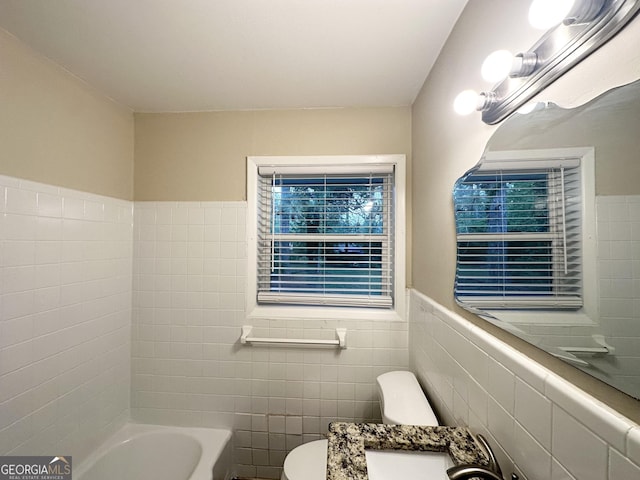 bathroom with toilet, tile walls, and wainscoting