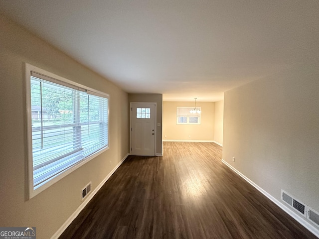 interior space featuring baseboards, a notable chandelier, dark wood-style floors, and visible vents