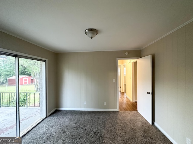 spare room with baseboards, ornamental molding, carpet flooring, and wood walls