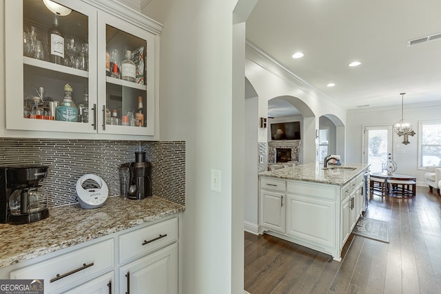 2225 Independence Ln, Buford, GA 30519 - kitchen featuring crown molding, light stone counters, glass insert cabinets, decorative backsplash, and white cabinets