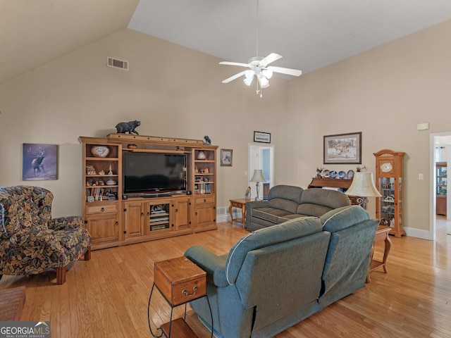 living area with ceiling fan, visible vents, high vaulted ceiling, baseboards, and light wood finished floors