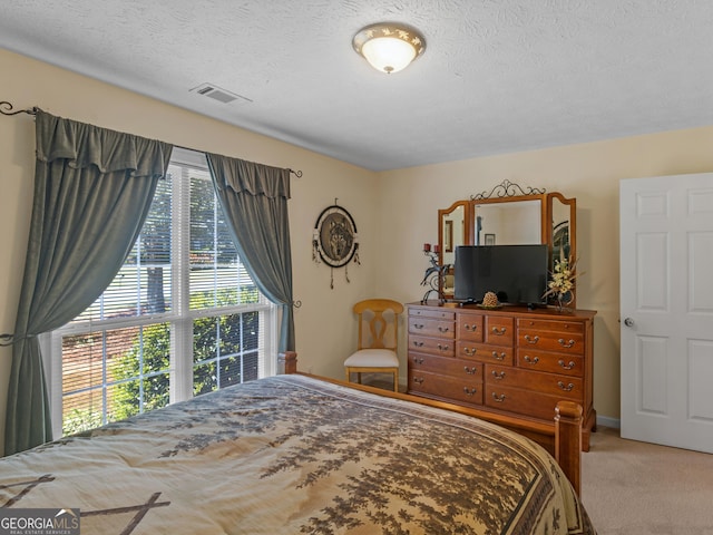 carpeted bedroom featuring a textured ceiling and visible vents