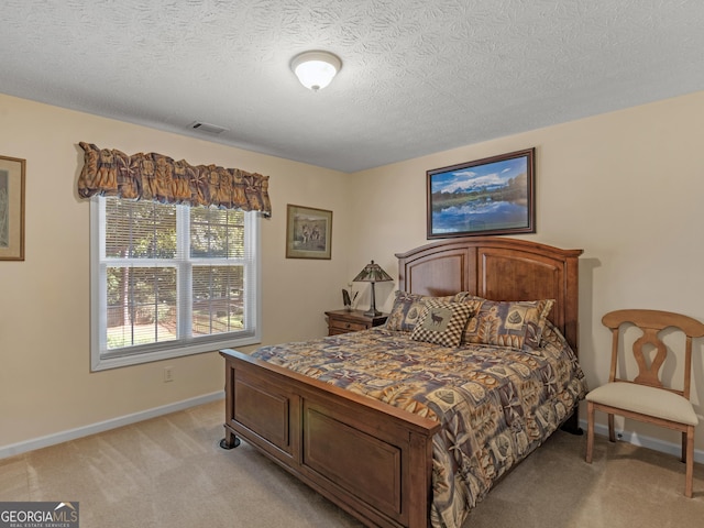 bedroom featuring visible vents, a textured ceiling, baseboards, and light colored carpet