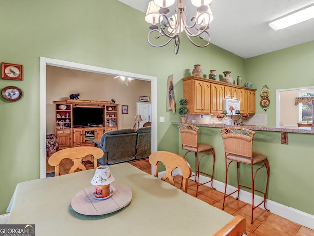 dining space with baseboards, light tile patterned floors, a chandelier, and high vaulted ceiling