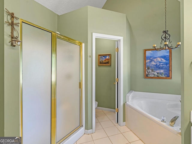bathroom featuring tile patterned flooring, a notable chandelier, a shower stall, and a garden tub
