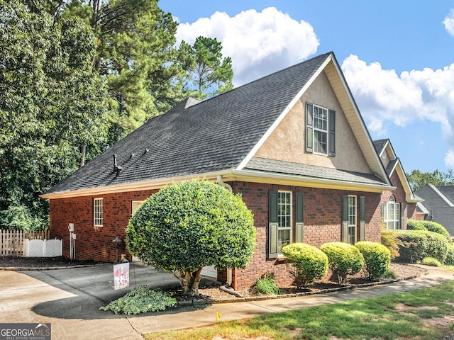 view of front of property with fence, a shingled roof, stucco siding, and brick siding