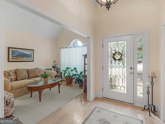 entryway with high vaulted ceiling, plenty of natural light, and light wood-style flooring