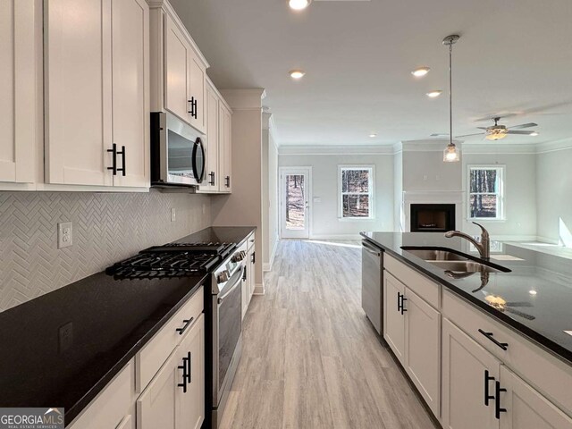 5321 Tuscany Dr, Douglasville, GA 30135 - kitchen with crown molding, dark countertops, open floor plan, stainless steel appliances, and light wood-style flooring