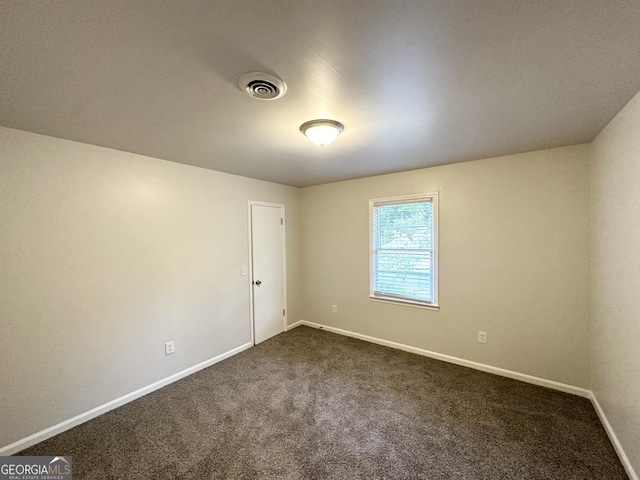 unfurnished room with baseboards, visible vents, and dark colored carpet
