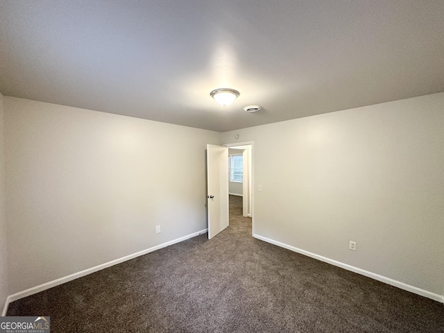 unfurnished bedroom featuring baseboards, visible vents, and dark carpet