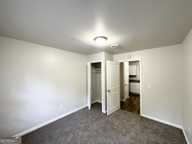 unfurnished bedroom with baseboards, a closet, and dark carpet