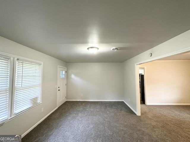 empty room with dark colored carpet and baseboards