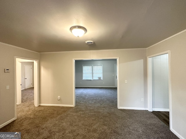 spare room featuring ornamental molding, dark carpet, and visible vents
