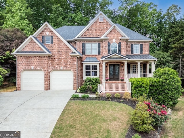 view of front facade with a porch, a standing seam roof, a front yard, brick siding, and concrete driveway