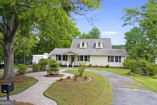 cape cod home with curved driveway, a porch, and a front yard
