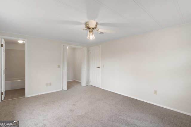 unfurnished bedroom featuring carpet floors, baseboards, ceiling fan, and ensuite bathroom