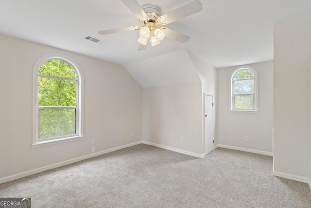 additional living space featuring carpet flooring, a ceiling fan, baseboards, vaulted ceiling, and visible vents