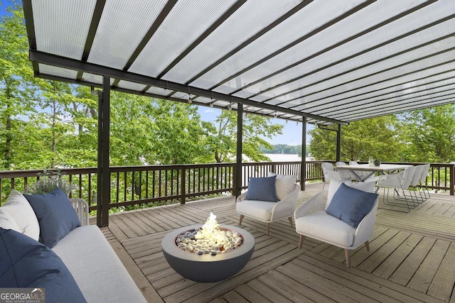 wooden deck featuring outdoor dining area, an outdoor living space with a fire pit, and a water view