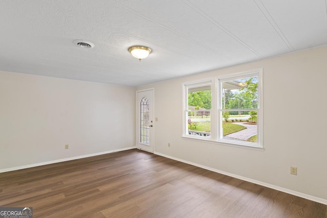 empty room featuring visible vents, baseboards, and wood finished floors