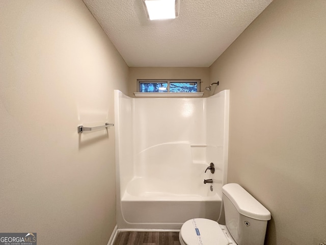 263 Coral Cir, Mcdonough, GA 30253 - full bathroom with wood finished floors, bathing tub / shower combination, toilet, baseboards, and a textured ceiling