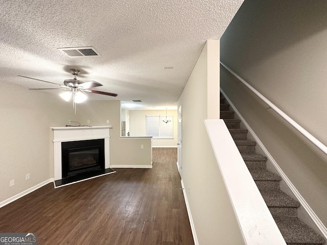 263 Coral Cir, Mcdonough, GA 30253 - unfurnished living room with a textured ceiling, dark wood finished floors, ceiling fan, and a glass covered fireplace