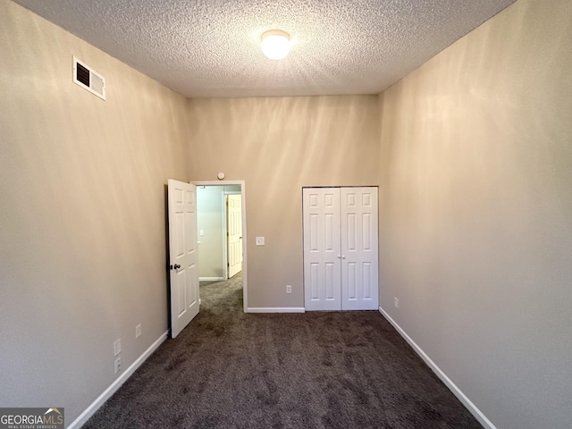 263 Coral Cir, Mcdonough, GA 30253 - unfurnished bedroom with a textured ceiling, visible vents, baseboards, a closet, and dark colored carpet