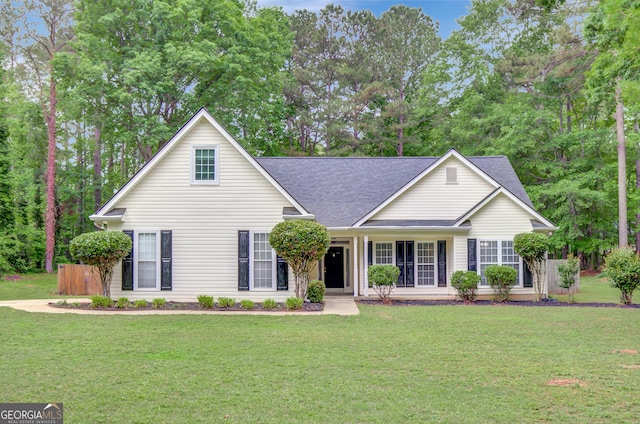 view of front facade with covered porch, a shingled roof, and a front lawn