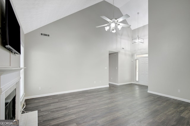 unfurnished living room with dark wood-style flooring, ceiling fan, high vaulted ceiling, and a tile fireplace