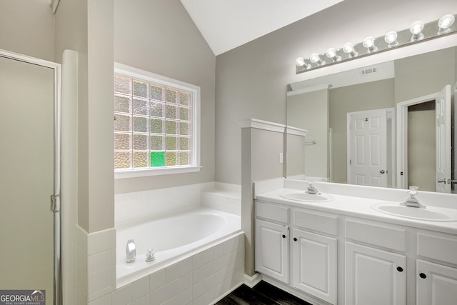 full bathroom featuring a bath, double vanity, a sink, and lofted ceiling