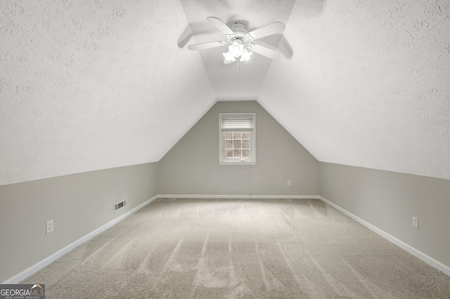 additional living space with a ceiling fan, a textured ceiling, and lofted ceiling