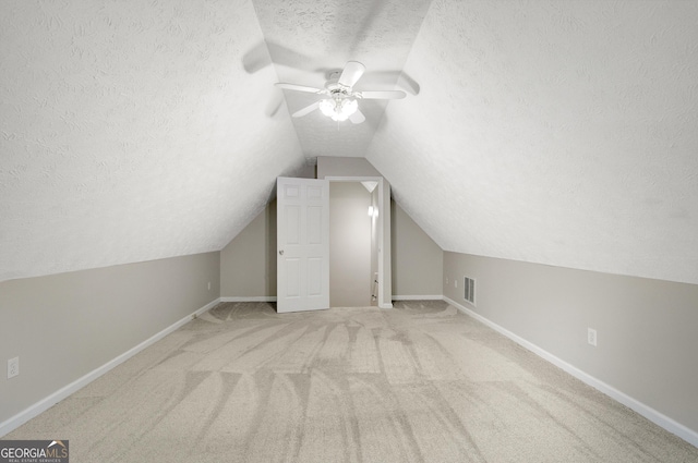 additional living space with visible vents, lofted ceiling, ceiling fan, a textured ceiling, and carpet
