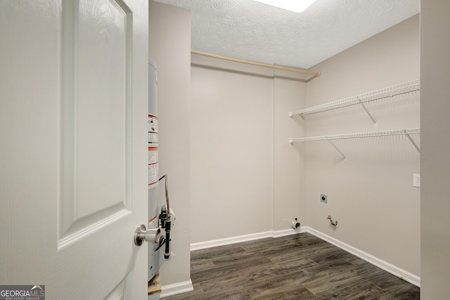 clothes washing area featuring laundry area, baseboards, dark wood-type flooring, electric dryer hookup, and hookup for a gas dryer
