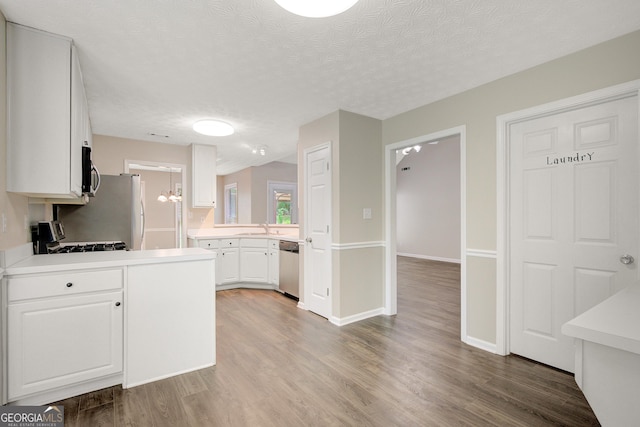 kitchen featuring a sink, light countertops, stainless steel appliances, and wood finished floors