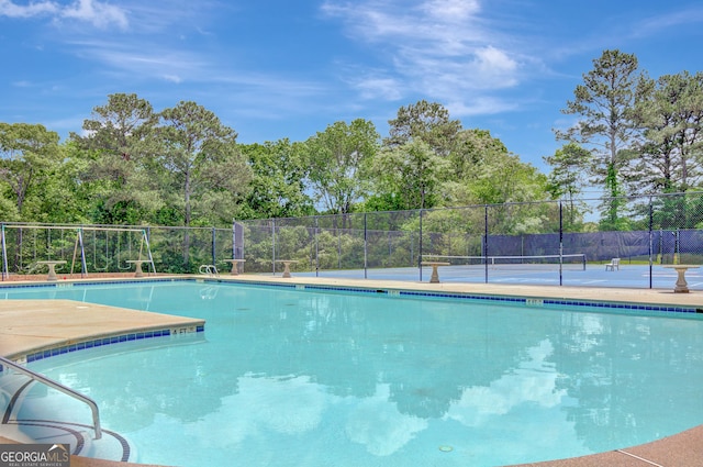 pool with fence and a tennis court