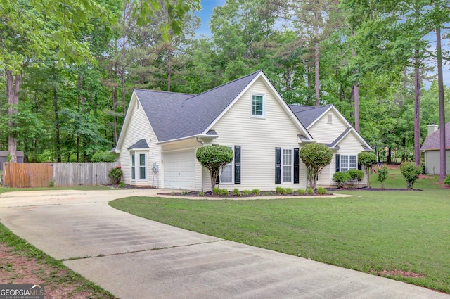 view of front facade with fence, a front yard, a shingled roof, concrete driveway, and an attached garage