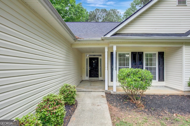 property entrance featuring roof with shingles and covered porch