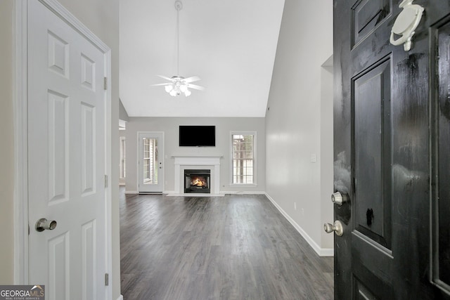 unfurnished living room with ceiling fan, high vaulted ceiling, baseboards, wood finished floors, and a high end fireplace