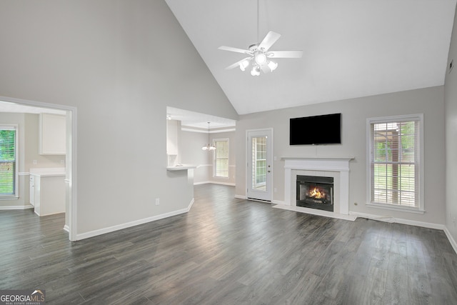 unfurnished living room featuring baseboards, a fireplace with flush hearth, ceiling fan with notable chandelier, and high vaulted ceiling