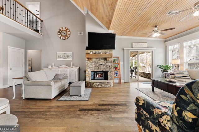 living area featuring a ceiling fan, wooden ceiling, crown molding, a towering ceiling, and a fireplace