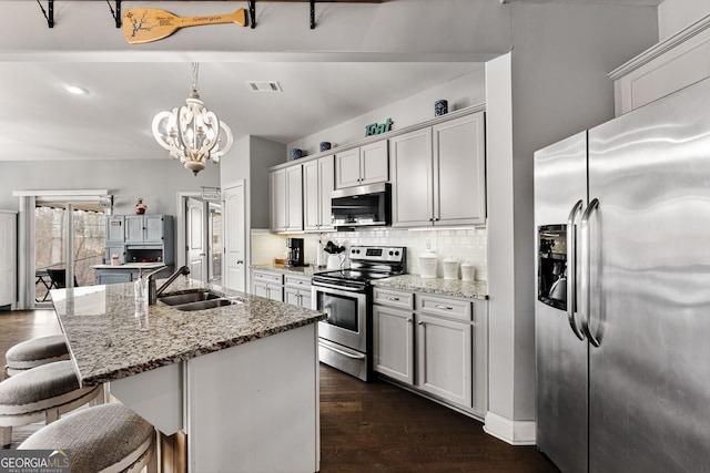 kitchen with appliances with stainless steel finishes, a sink, tasteful backsplash, a kitchen breakfast bar, and a chandelier