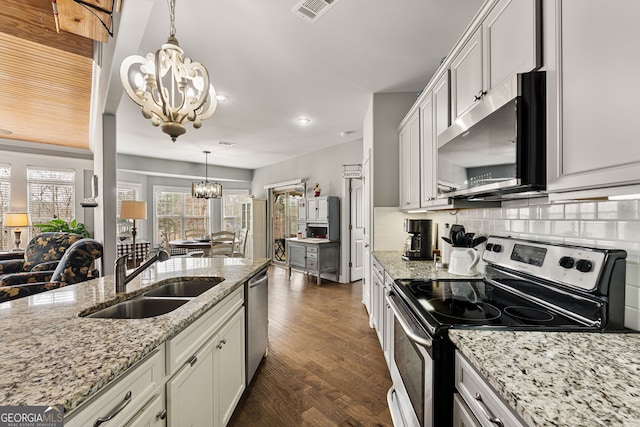 kitchen with a chandelier, appliances with stainless steel finishes, a sink, tasteful backsplash, and dark wood-type flooring
