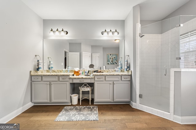 bathroom with a stall shower, wood finished floors, baseboards, and vanity