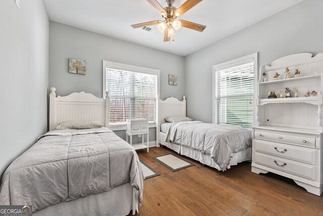 bedroom with dark wood-style flooring, multiple windows, and ceiling fan