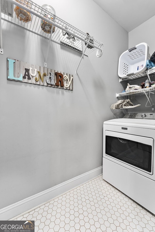 clothes washing area featuring tile patterned floors and baseboards